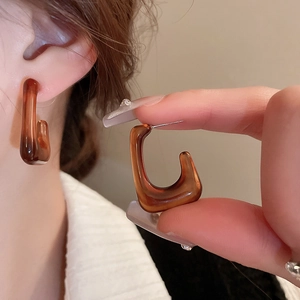 Close-up of geometric amber resin earrings in U-shaped minimalist design with silver pins