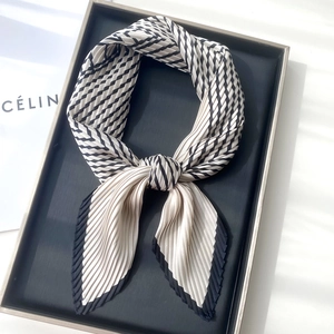 Detailed view of pleated black and white striped silk scarf with elegant edge stitching