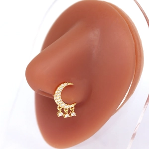 Détail d'un piercing de nez lune dorée avec cristaux brillants et trois petits pendentifs