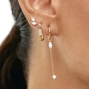 Close-up of stacked gold earrings with marquise-cut zircon and long chain pendant