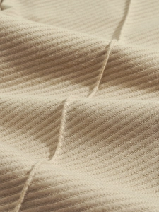 Vista dettagliata del tessuto a maglia a coste color avena con morbido drappeggio