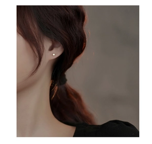 Gros plan d'une boucle d'oreille en opale minimaliste dorée portée sur le lobe d'une femme