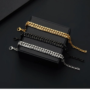 Close-up of gold, black and silver Cuban link bracelets on a black jewelry gift box