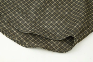 Close-up of olive green plaid shirt hem with durable double stitching and side slit detail