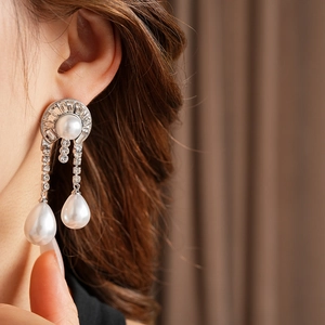 Dettaglio di orecchini pendenti in argento con perle bianche e zirconi brillanti