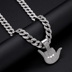 Macro shot of silver hip-hop cuban chain with iced-out gesture pendant on black leather