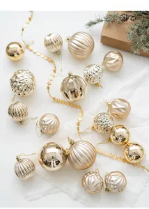 Gros plan de boules de Noël dorées aux textures variées sur tissu avec décor de sapin