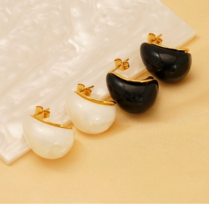 Detailed shot of teardrop earrings in black and pearl white with 18K gold plated finish