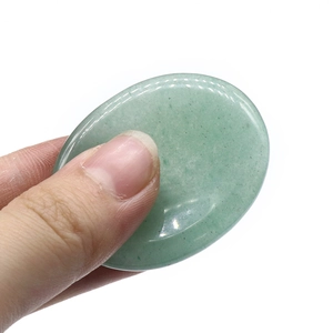 Polished green jade thumb worry stone for facial scraping massage being held by hand