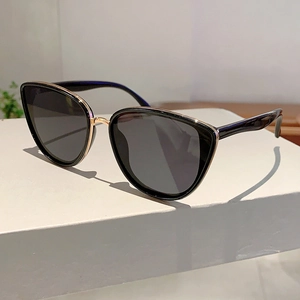 Side view of chic black cat eye sunglasses with gold trim on a white display block