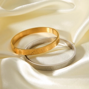 Detail of Roman numeral engraved bangles in gold and silver finish on silk
