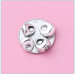 Macro shot of four S925 solid silver charms on a coin showing mini DIY size and texture