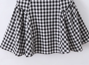 Detailed macro view of black and white gingham dress showing side shirring and woven texture