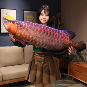 Close-up of a giant vibrant red dragon fish plush pillow held by a model in a cozy living room