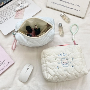 Detail of embroidered rabbit on quilted heart cosmetic bag in a lifestyle office setting