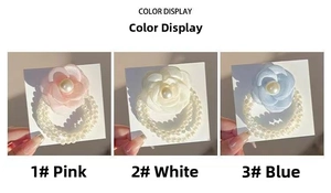 Detailed close-up of camellia flower hair ties with pearls in pink, white, and blue colors