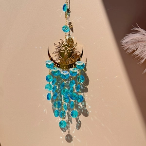 Detail of golden sun and moon suncatcher with blue crystal beads reflecting light