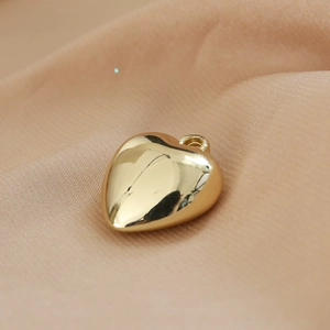Close-up of golden heart pendant on silk background for jewelry making DIY
