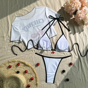 Flat lay of a three-piece cherry print bikini set with mesh t-shirt and cherry charms