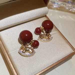 Detailed view of 18K gold plated horse earrings with red beads and sparkling zircons