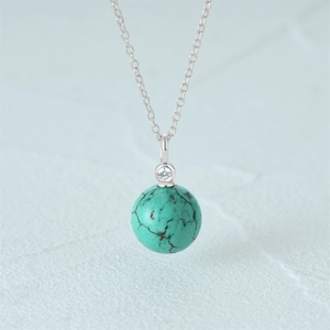 Macro shot of turquoise stone pendant with silver chain on textured background