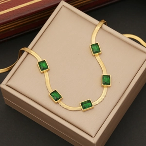 Golden flat snake chain necklace with five emerald green square stones on beige box