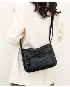 Detail of black vintage crossbody bag showing soft pebble leather and zip pockets