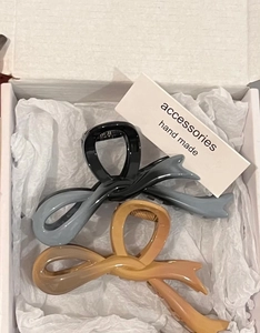 Detail of gradient blue and amber resin bow hair claws inside a white gift box