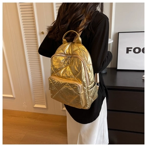 Detail des goldenen gesteppten Rucksacks mit großen Rautenmustern und weicher Textur