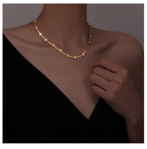 Detail of matte gold snake bone choker with small round discs on model's neck