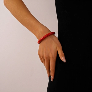 Detailed shot of a red acrylic bangle with black marble texture on a model's wrist