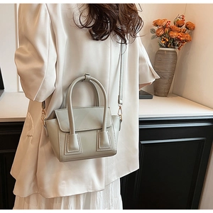 Detail of light grey-green bucket bag showing top handle and adjustable shoulder strap