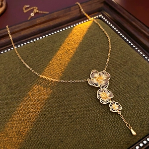 Detailed view of a gold flower tassel necklace on dark green fabric with dramatic lighting