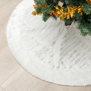 Close-up of a white plush Christmas tree skirt with silver sequin embroidery on wood floor
