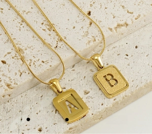 Detailed close-up of hollow gold A and B letter pendants on a snake bone chain necklace