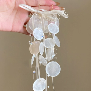 Detailed shot of bow earrings featuring iridescent beads and pearl shell fringe