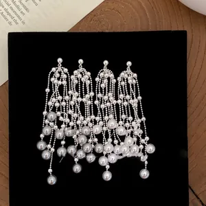 Detail view of silver tassel pearl drop earrings on a black velvet display background