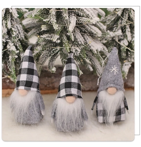 Close-up of three handmade Christmas gnomes with grey and buffalo plaid hats in snow