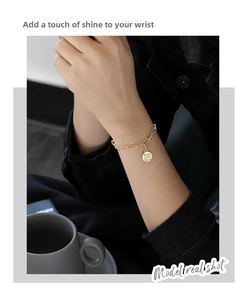 Detail of gold coin bracelet with Trust in the Lord engraving on a thick chain link