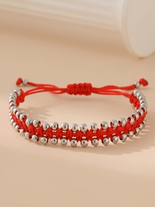 Détail d'un bracelet en corde rouge tissée à la main avec perles en acier inoxydable