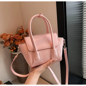 Detailed view of pink trapezoidal bucket bag with top handles and adjustable strap