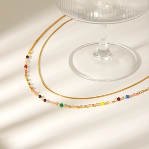Detail of double-layer gold snake chain with colored beads on a white background