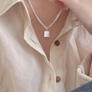 Detail of 925 sterling silver square pendant on cuban chain necklace worn by a model