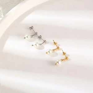 Close-up of elegant C-shaped stainless steel earrings with white pearls in gold and silver