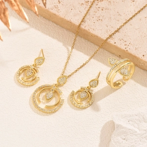 Parure de bijoux dorés avec zircons en forme de goutte sur fond de pierre