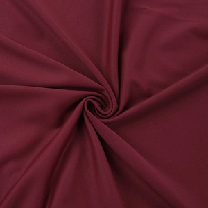 Macro detail of the dark red stretch knit fabric with a smooth textured spiral twist