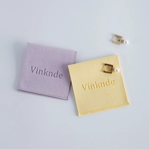Micro shot of purple and yellow velvet jewelry pouches with pearl square earrings
