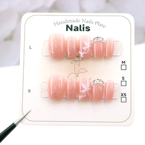 Detailed close-up of handmade pink gradient press-on nails with glitter and floral art