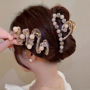 Detail of gold metal hair clips with beige pearls and rhinestones on hair