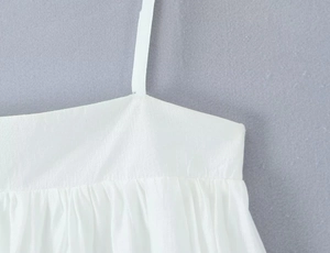 Detailed macro view of white camisole straps with pleated chest line and stitch details